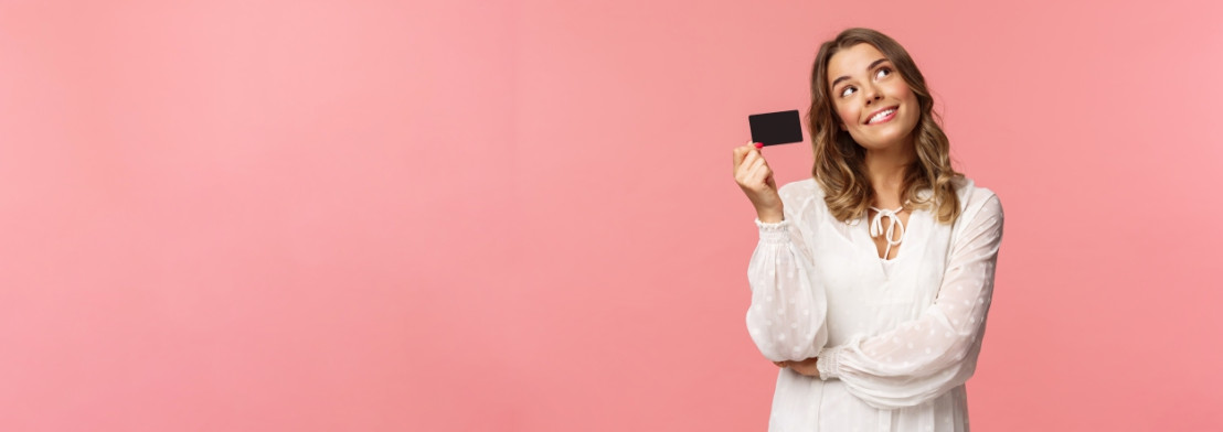 Vrouw heeft cadeaubon in hand en kijkt heel blij en vraagt zich wat ze er voor zal kopen